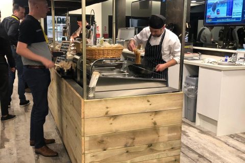 A person cooking, while using a big kahuna food cart