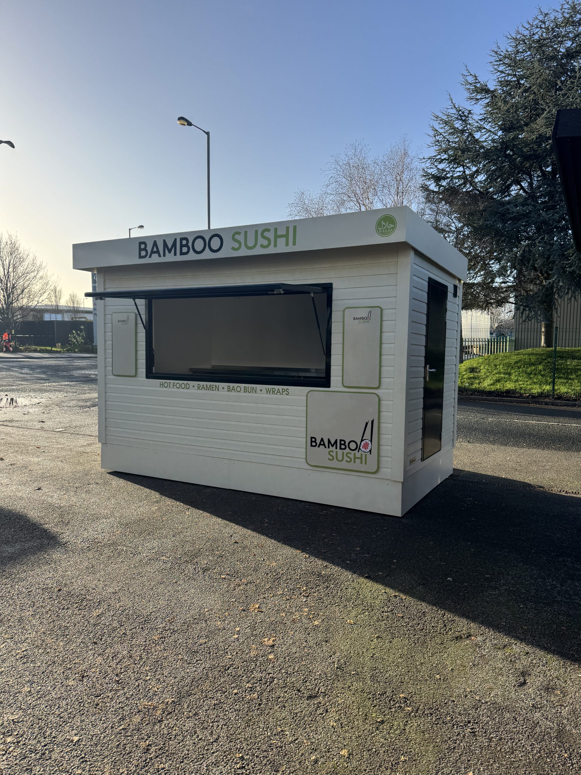 Compact food pod unit with stainless steel counters and serving hatch, ideal for mobile catering.